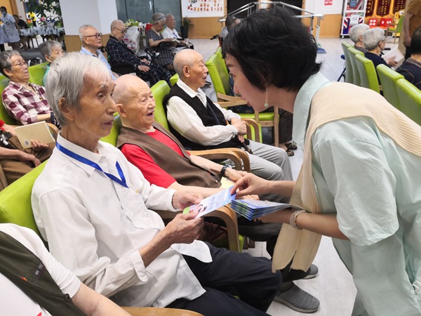 工作人員向老年人發(fā)放防詐手冊(cè)。九龍坡區(qū)市場監(jiān)督管理局供圖