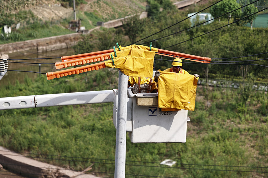 電力公司工作人員在電線上鋪上絕緣毯。國(guó)網(wǎng)重慶市電力公司供圖