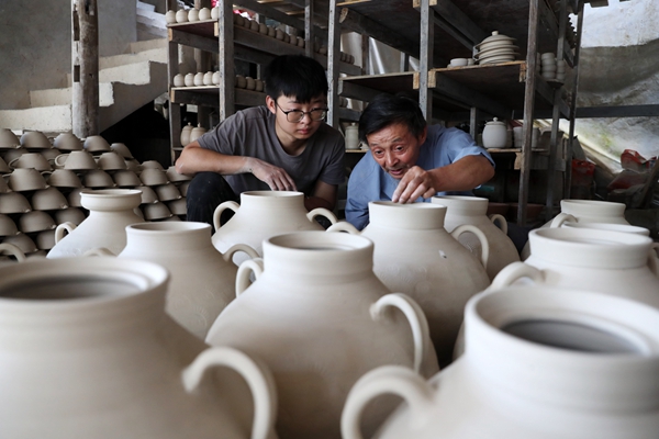 羅達川（左）跟劉沛良學檢查陶坯的質(zhì)量。黔江區(qū)委宣傳部供圖