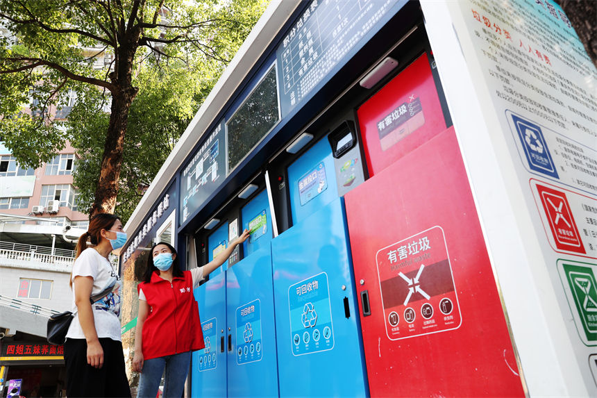 在生活垃圾分類服務(wù)驛站,管理員(右)在給市民講解使用垃圾智能分類的方法。楊敏攝