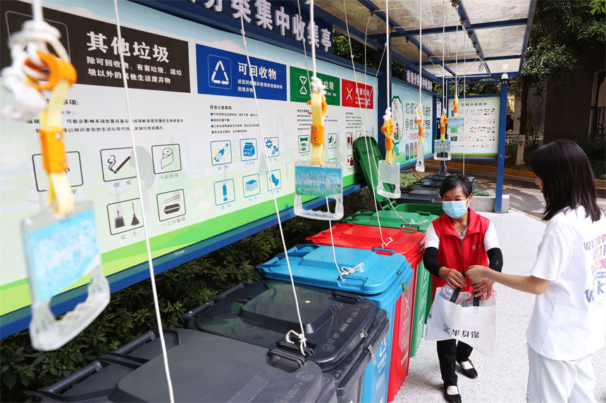 在當?shù)厍堦栮P(guān)國際小區(qū)垃圾分類集中收集亭，垃圾分揀員（左）指導(dǎo)市民垃圾分類。楊敏攝