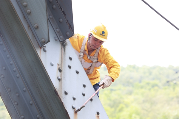 烈日下鮮志榮爬上鋼梁大橋檢查連接螺栓。晏濤攝