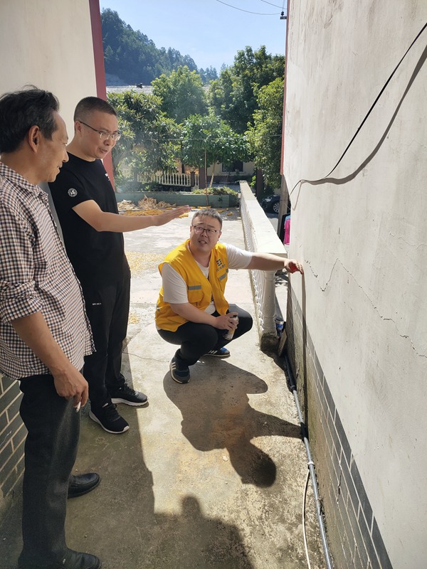 《炎炎夏日，地災巡查力度不減》。8月9日，107地質隊駐守隊員與沙壩鎮(zhèn)群測群防員頭頂烈日在萬慶村地質災害隱患點開展日常巡查，現場分析墻體裂縫形成的原因。路正昆攝