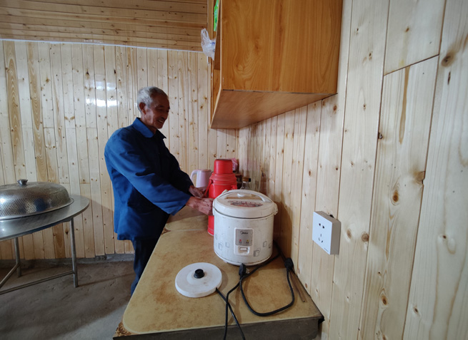 杉板裝飾的屋內(nèi)，老黨員正熱情地給客人們倒茶。徐俊聰攝