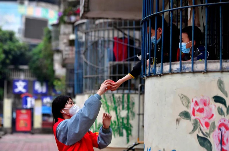 11月18日，南岸區(qū)長生橋鎮(zhèn)桃花橋社區(qū)移民小區(qū)，一位小朋友為正在小區(qū)巡查的大學(xué)生志愿者李江玲送上了一個(gè)蘋果。此次共有35名來自重慶多所高校的志愿者參加到長生橋鎮(zhèn)的疫情防控工作中。王雄 攝