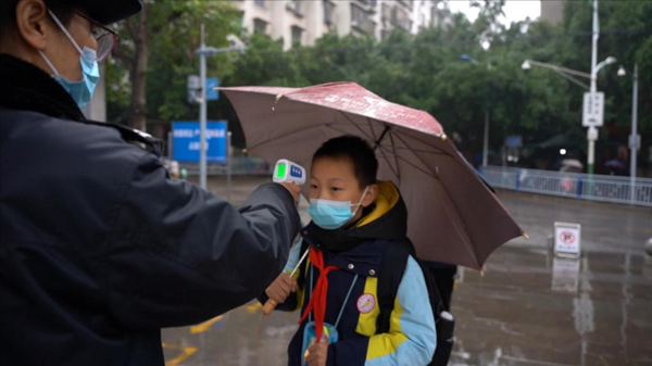 門衛(wèi)對進校學(xué)生進行體溫檢測。楊安東攝