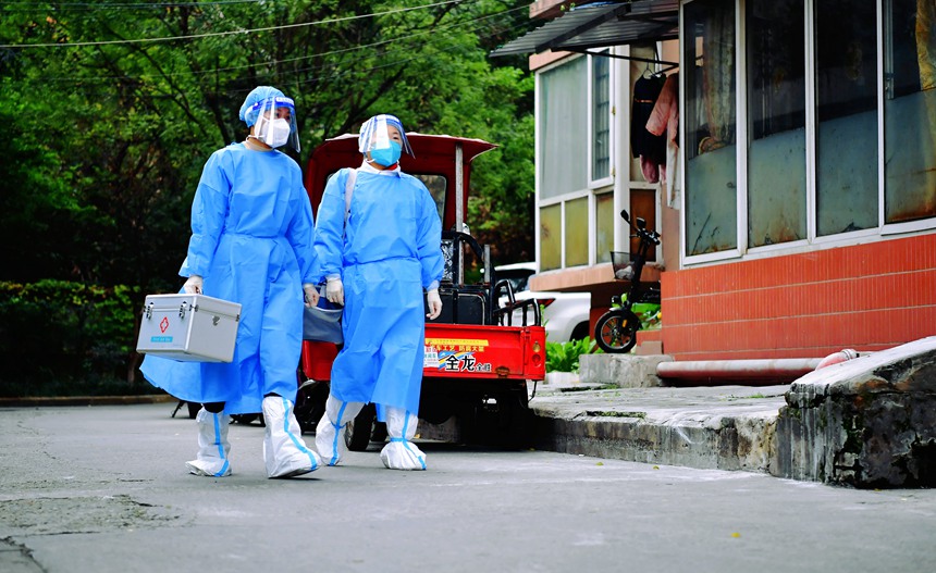 社區(qū)工作人員和醫(yī)護(hù)人員在轄區(qū)宣傳疫苗接種。周舸攝