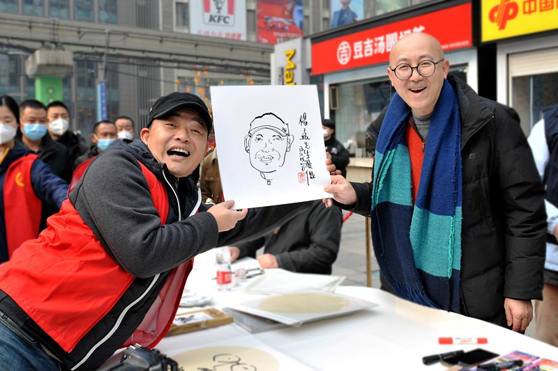 游江（右）為現(xiàn)場(chǎng)市民作畫。受訪者供圖