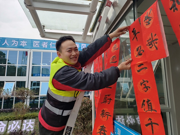 建設(shè)者將寫(xiě)好的春聯(lián)掛上。
