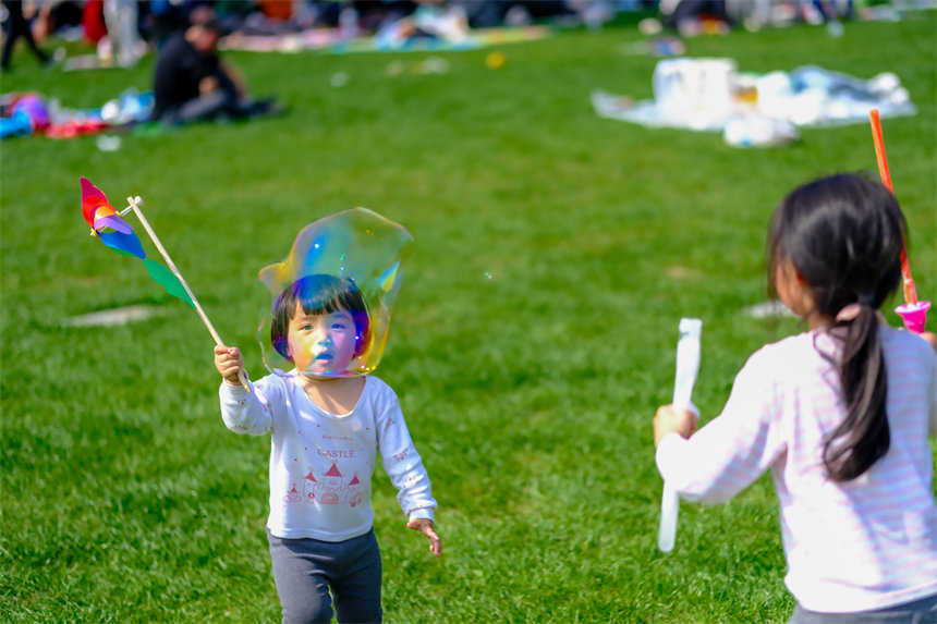 小朋友在草坪上嬉戲玩耍。郭旭攝