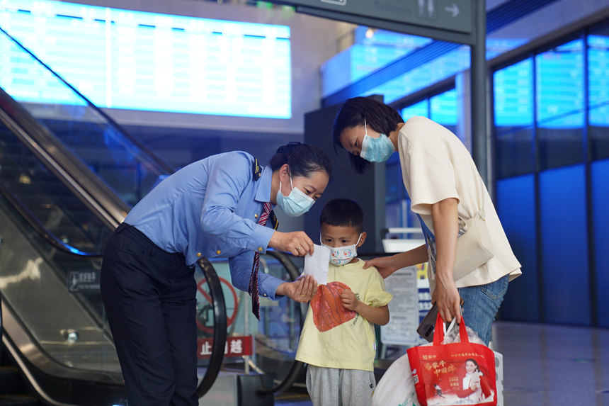 重慶北站工作人員正在為小旅客講解行程提示單。汪亮攝