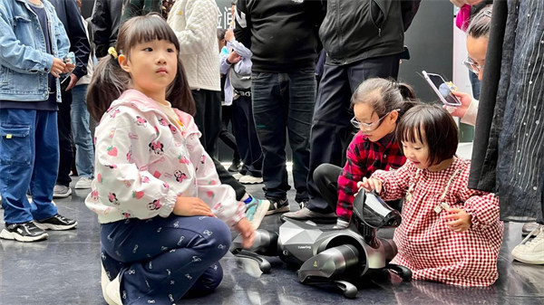 小朋友們與機器狗做游戲。馬春鵬攝