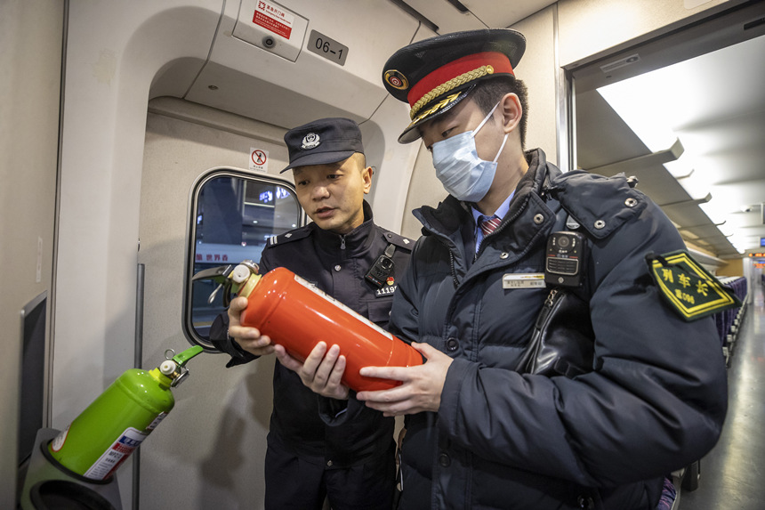 彭聰（左一）在列車長的配合下，對列車配備的滅火器進(jìn)行檢查。胡勇攝