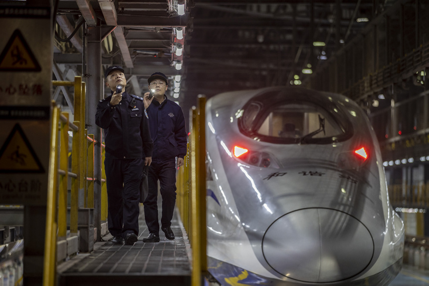 彭聰（左一）在重慶北動車所工作人員的配合下，對檢修庫作業(yè)線上的電路阻燃絕緣防護(hù)進(jìn)行檢查。胡勇攝