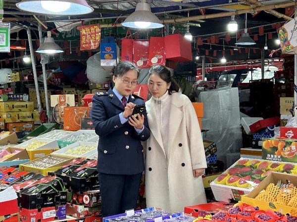 江津區(qū)稅務(wù)人員到雙福國際農(nóng)貿(mào)城輔導(dǎo)商戶使用“農(nóng)品慧”平臺。王露洪攝