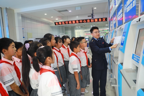 在長壽區(qū)辦稅服務(wù)廳，同學們正認真聽稅務(wù)人員講解發(fā)票代開機的操作步驟和發(fā)票的相關(guān)知識。袁洪昊攝