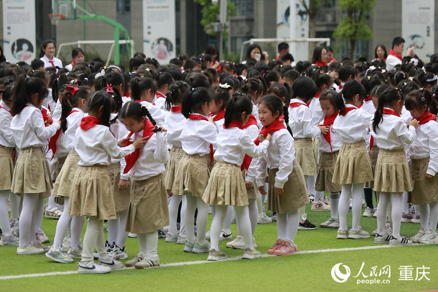 高年級學(xué)生為新入隊的少先隊員佩戴紅領(lǐng)巾。人民網(wǎng)記者 劉政寧攝