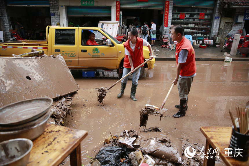 志愿者清理仁沙鎮(zhèn)場鎮(zhèn)的淤泥和雜物。人民網(wǎng)記者 劉政寧攝