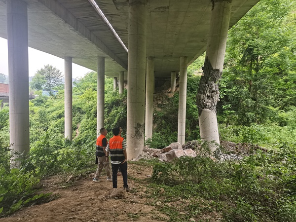 《橋梁受損急人心 搶險(xiǎn)應(yīng)急護(hù)安全》。5月21日，川東南勘察公司駐守地質(zhì)工程師潘笑天（右）、宋宏平會(huì)同相關(guān)專家，對(duì)黔江區(qū)阿蓬江鎮(zhèn)犁灣龍洞溝大橋危巖崩塌損毀橋墩處進(jìn)行應(yīng)急處置。目前,龍洞溝大橋損毀橋墩已完成更換，橋墩內(nèi)側(cè)已安裝被動(dòng)防護(hù)網(wǎng)。傅柯榮攝