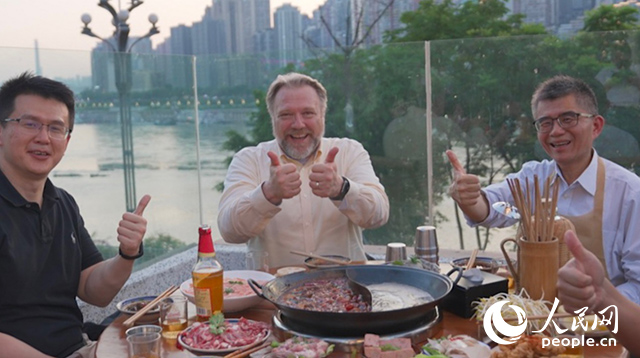 康寧顯示科技事業(yè)部全球拓建項(xiàng)目總監(jiān)軻寶華（中）和同事在重慶南濱路吃火鍋。人民網(wǎng)記者 蘇纓翔攝
