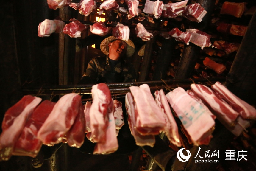 工人將腌制好的豬肉掛入炕房。人民網(wǎng)記者 劉政寧攝