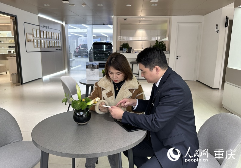 王女士在工作人員的指引下用手機辦理新車上牌業(yè)務。人民網記者 劉政寧攝