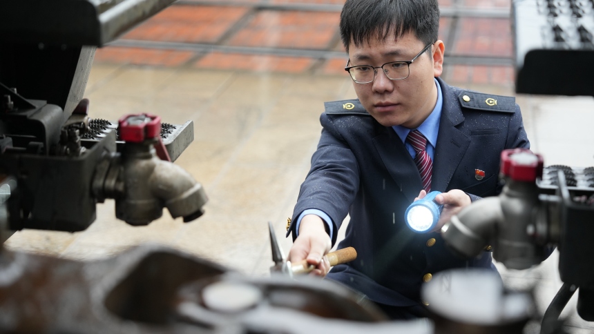 中歐班列發(fā)車前，謝嗣航正在對機車走行部關鍵部件進行檢查。周彥超攝