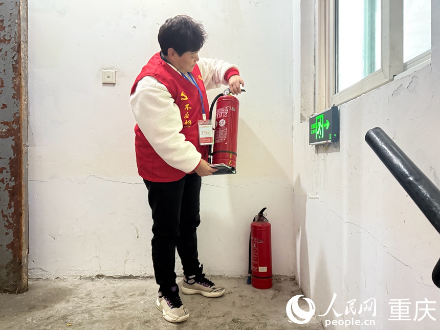 文登群認(rèn)真檢查樓梯間擺放的滅火器是否能正常使用。人民網(wǎng)記者 胡虹攝
