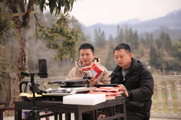 孫和發(fā)（左一）帶領(lǐng)返鄉(xiāng)創(chuàng)業(yè)大學(xué)生冉春生直播講解本地品牌“千丘原鄉(xiāng)”火鍋底料。謝紹春攝