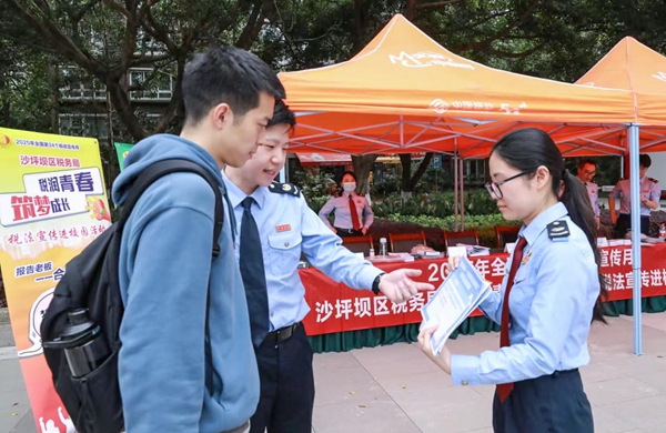 沙坪壩區(qū)稅務(wù)人員在四川外國語大學(xué)設(shè)置宣傳點，向往來學(xué)生發(fā)放宣傳冊，邀請其參與合規(guī)經(jīng)營情景模擬，樹立合規(guī)經(jīng)營意識。郭亞玲 攝