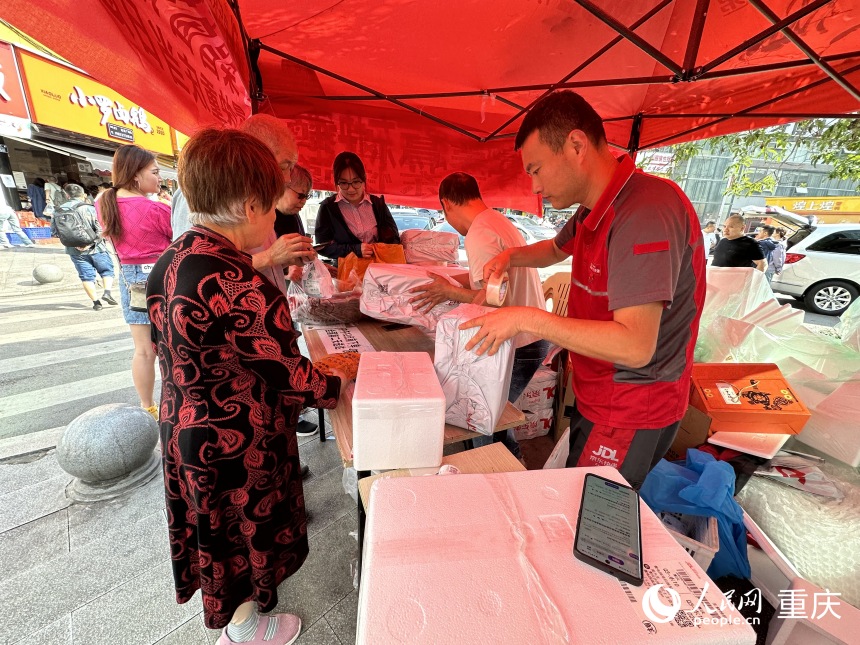 劉琦（右三）在快遞點(diǎn)將鹵鵝打包郵寄。人民網(wǎng)記者 劉政寧攝