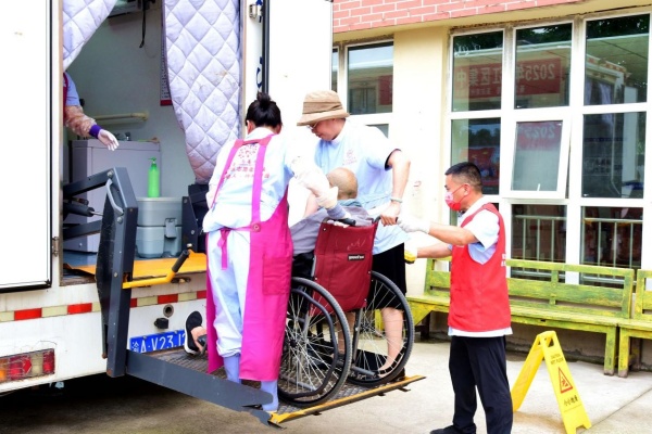 志愿者扶老人進(jìn)入助浴車。楊晨攝