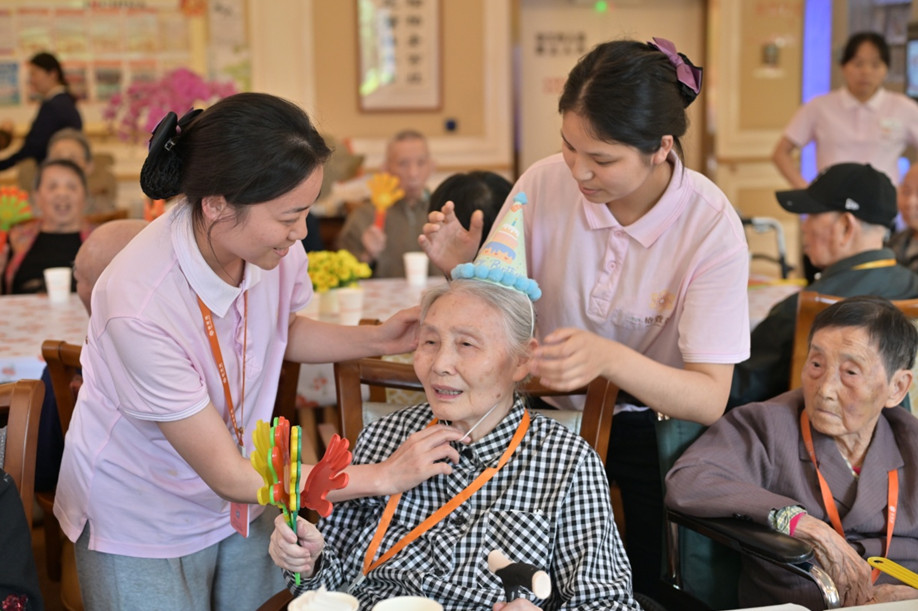 養(yǎng)老機(jī)構(gòu)工作人員為壽星老人們戴上生日帽，情暖老人心。程佩玉攝