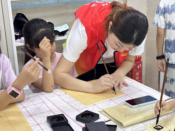 志愿者幫助孩子們?cè)谀阒懈惺軅鹘y(tǒng)文化魅力。唐彬貴攝