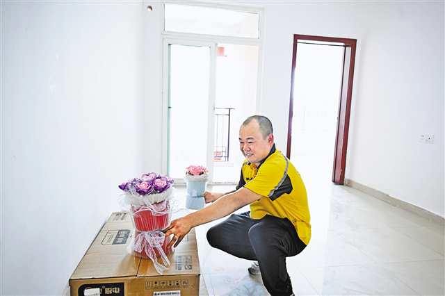 7月16日，空港樂園公租房小區(qū)，外賣員劉進(jìn)波迫不及待地將妻子做的手工花先放進(jìn)新家。