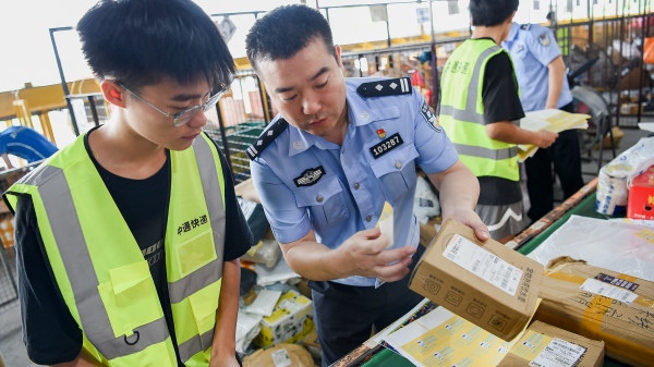 民警為快遞貼上反詐宣傳小貼紙。南岸區(qū)公安分局供圖
