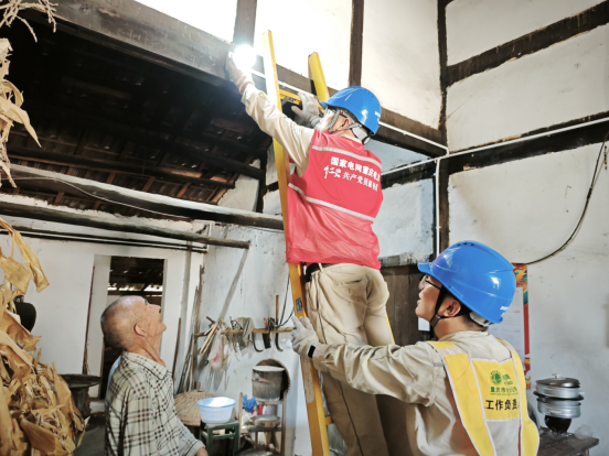 工作人員為老人整理線路并安裝節(jié)能燈。鐘雪攝