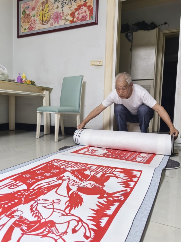 郭文友展示剪紙作品《銘記歷史 振興中華》。江津區(qū)委宣傳部供圖