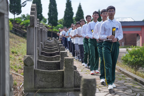 現(xiàn)場師生、黨員干部依次向周極明等烈士墓敬獻(xiàn)花。周久淞攝