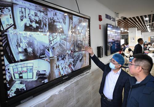 10月29日，位于兩江新區(qū)的兩江育才中學校食堂，學校工作人員和膳食委員會成員通過攝像頭查看售賣廳、庫房、冰箱區(qū)等區(qū)域的實時畫面。記者 張錦輝 攝/視覺重慶